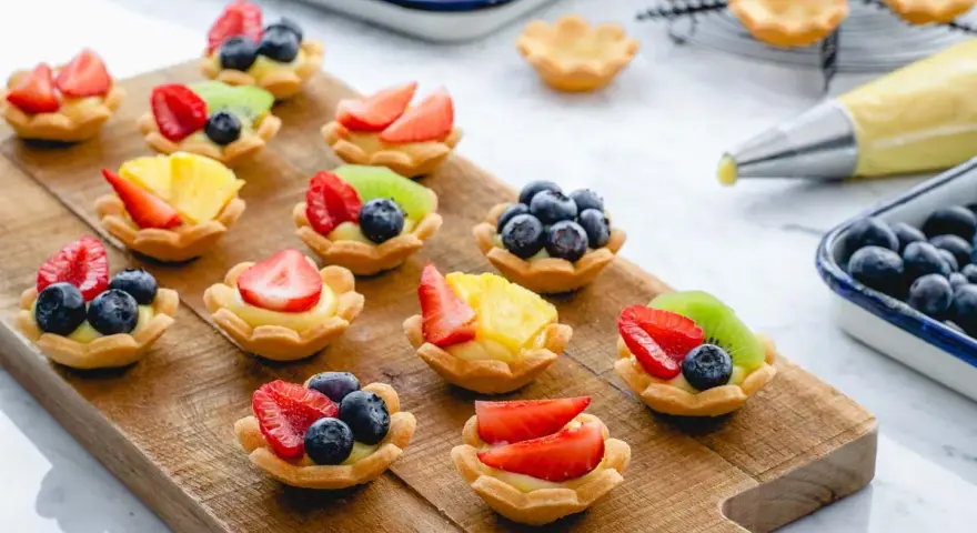 Deliziosi cestini di frutta ricetta, preparati con fragole, mirtilli, kiwi e ananas su una base di crema.