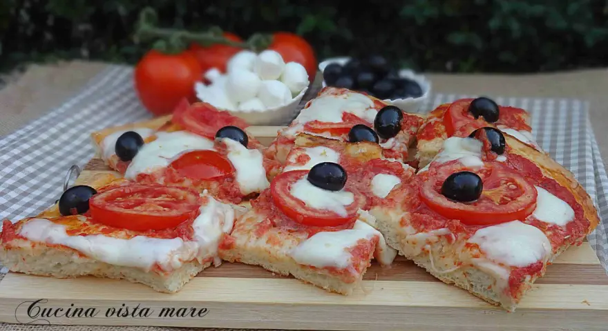 Fette di pizza saporita con pomodoro fresco, mozzarella filante e olive nere. Ingredienti semplici per un gusto autentico.