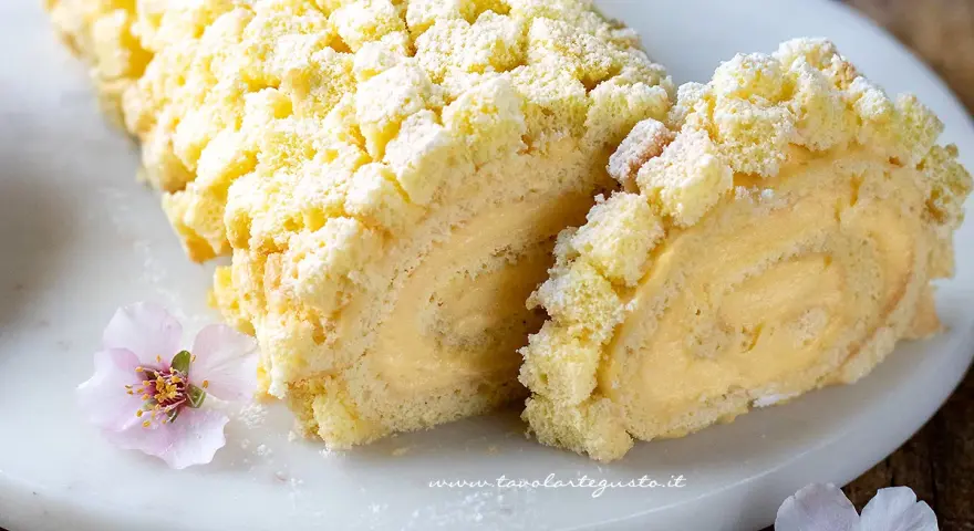 Tronchetto mimosa soffice e cremoso, decorato con briciole di pan di Spagna e fiori rosa.