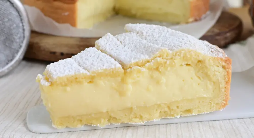 Fetta di crostata con abbondante crema allo yogurt, cosparsa di zucchero a velo.