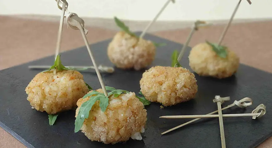 Deliziose polpette finger food con salsa, servite su una pietra scura, pronte per essere gustate.