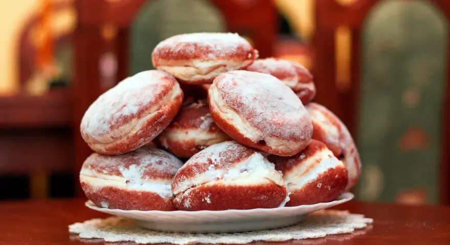 Pila di bomboloni zuccherati, pronti per il tłusty czwartek. Deliziosi dolcetti che invitano a festeggiare.
