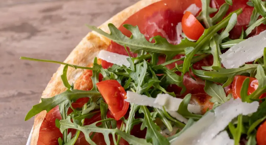 Pizza bresaola rucola e grana: un tripudio di sapori con bresaola, pomodorini, rucola fresca e scaglie di grana.