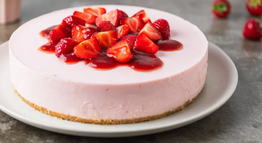 Cheesecake rosa con fragole fresche e salsa, un dolce delizioso, perfetto per ogni occasione.