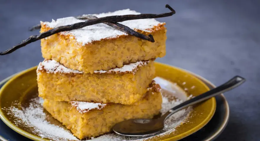 Tre fette impilate di torta di riso fiorentina, spolverate di zucchero a velo e decorate con baccelli di vaniglia.