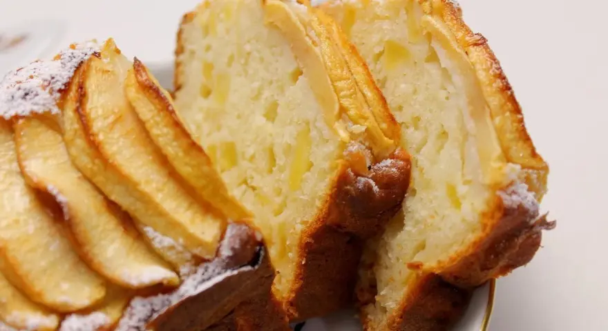 Fette di plumcake ricotta e mele, con mele a vista sulla superficie e spolverata di zucchero a velo.