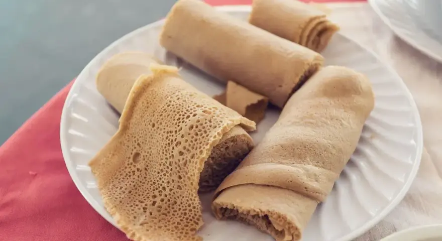 Piadina africana, un piatto di injera arrotolata, con la sua tipica trama alveolata, pronta per essere gustata.