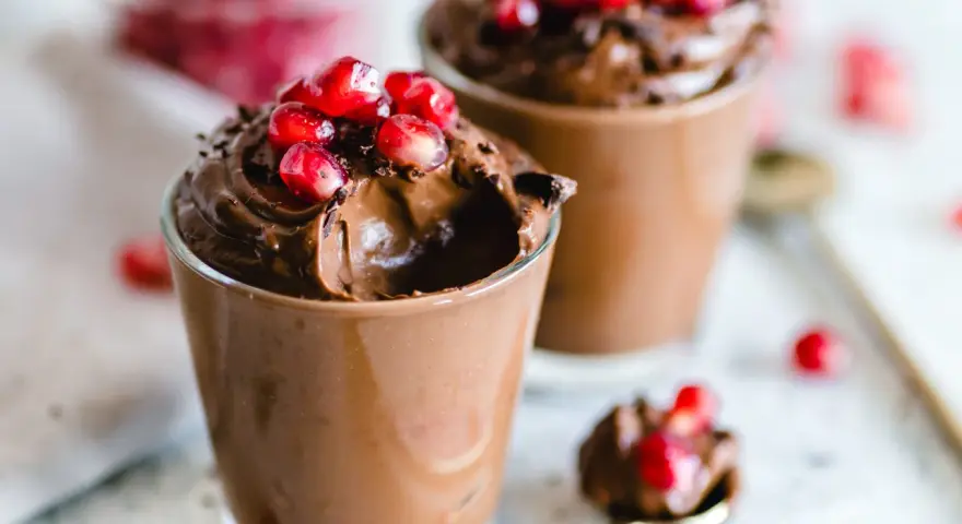 Mousse al cioccolato per profiterol, guarnita con chicchi di melagrana succosi. Un dessert goloso e invitante.