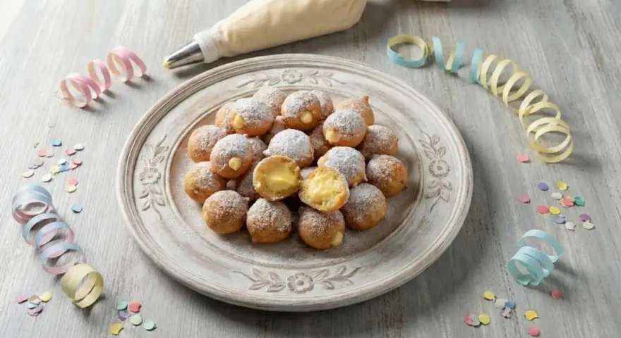 Castagnole ripiene di crema, spolverate di zucchero a velo, pronte per Carnevale. Un'idea golosa con yogurt greco per un tocco fresco.