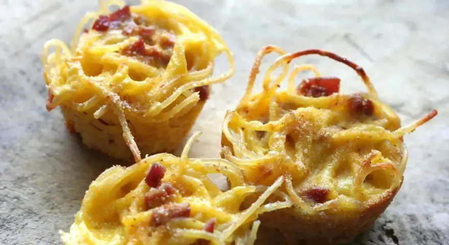 Tre tortini di pasta fritta senza glutine, dorati e croccanti, con pezzetti di pancetta.