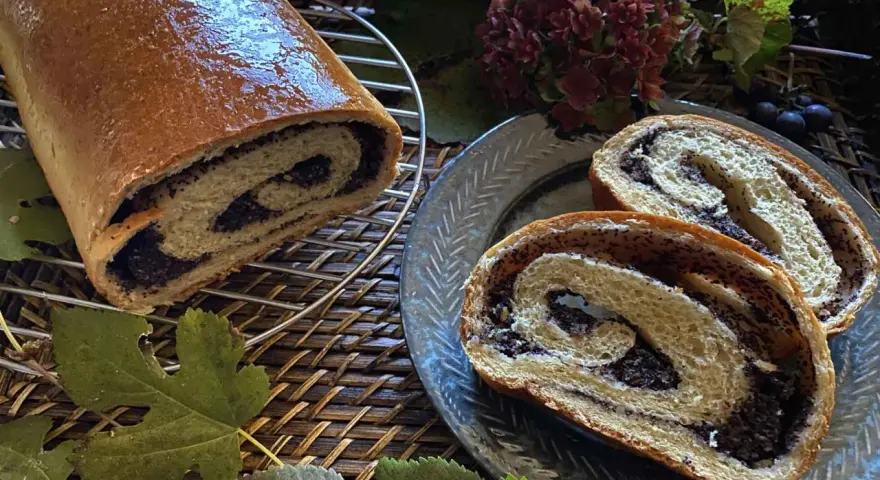 Makowiec japoński, un rotolo di pane dolce con ripieno di semi di papavero, tagliato a fette su un piatto decorato.