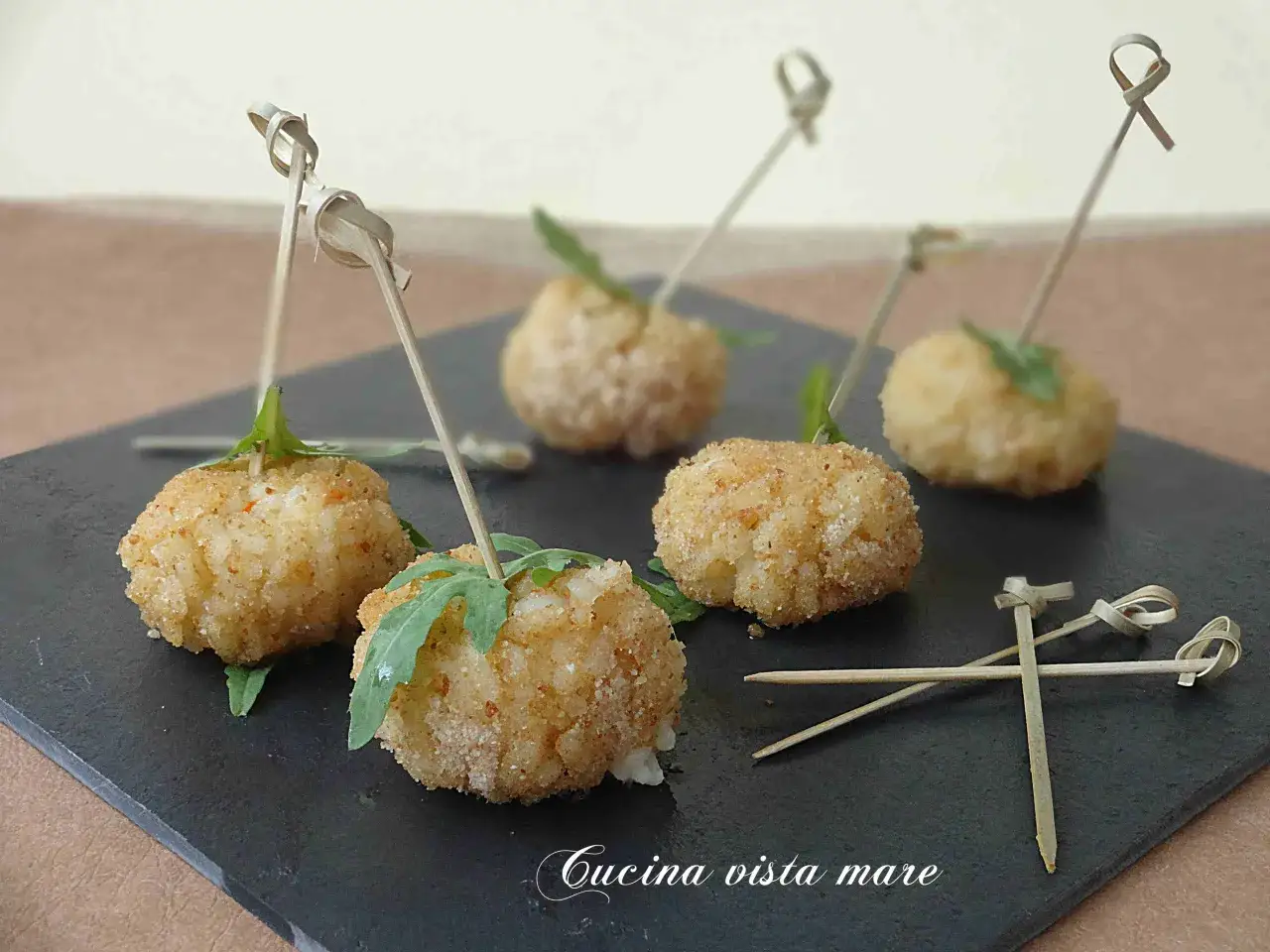 Deliziose polpette finger food con salsa, servite su una pietra scura con stuzzicadenti decorati.