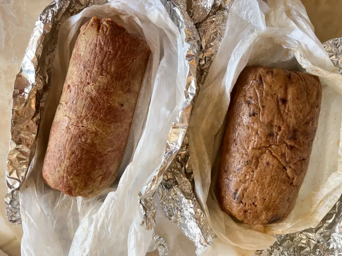 Due polpettoni di ceci, uno pi&ugrave; chiaro e uno pi&ugrave; scuro, avvolti in carta forno e alluminio, pronti per essere cotti.
