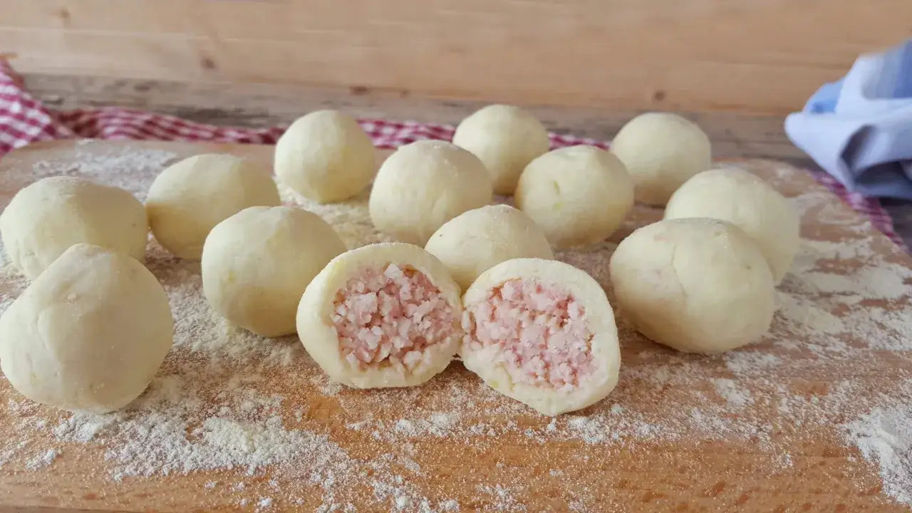 Un gruppo di gnocco di patate ripieno, uno tagliato a met&agrave; rivela un cuore saporito di carne.