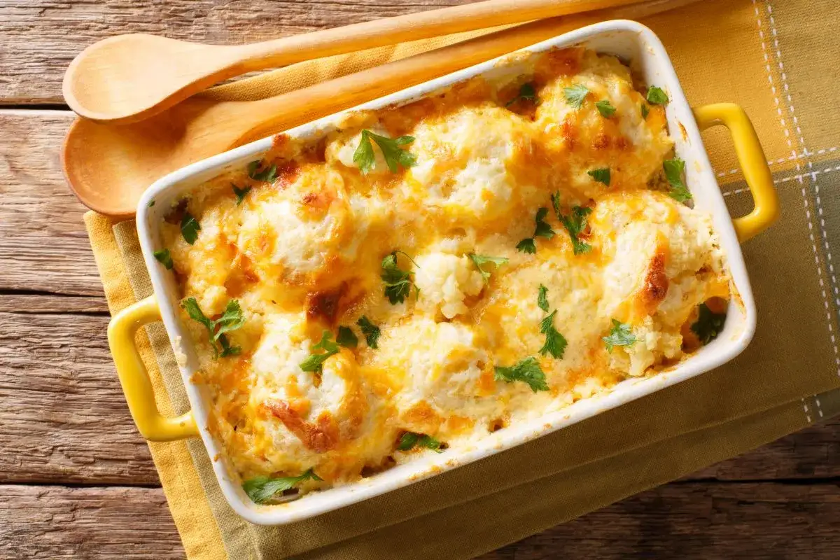 Sformato di cavolfiore e ricotta dorato e filante, guarnito con prezzemolo fresco, pronto per essere servito.