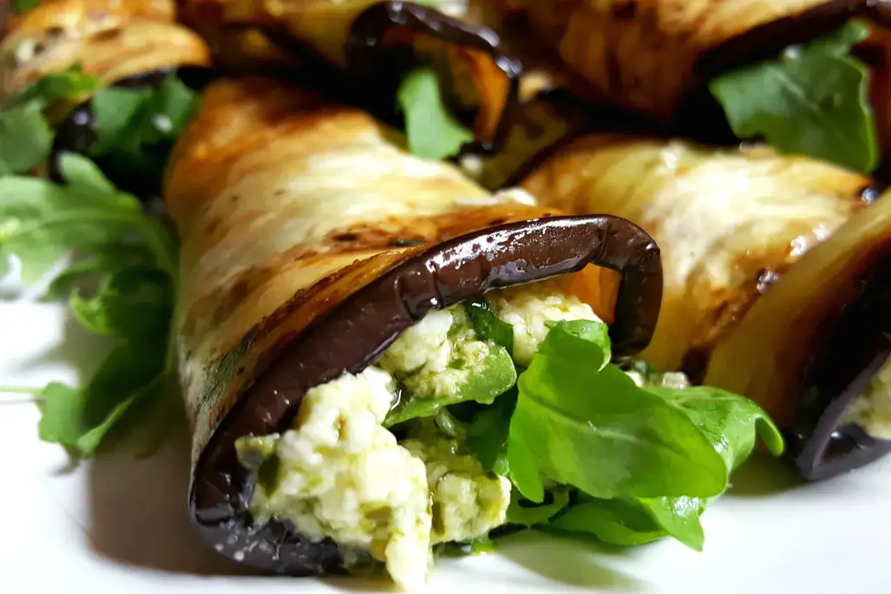 Deliziosi involtini di melanzane vegetariani ripieni di formaggio e rucola, un antipasto leggero e gustoso.