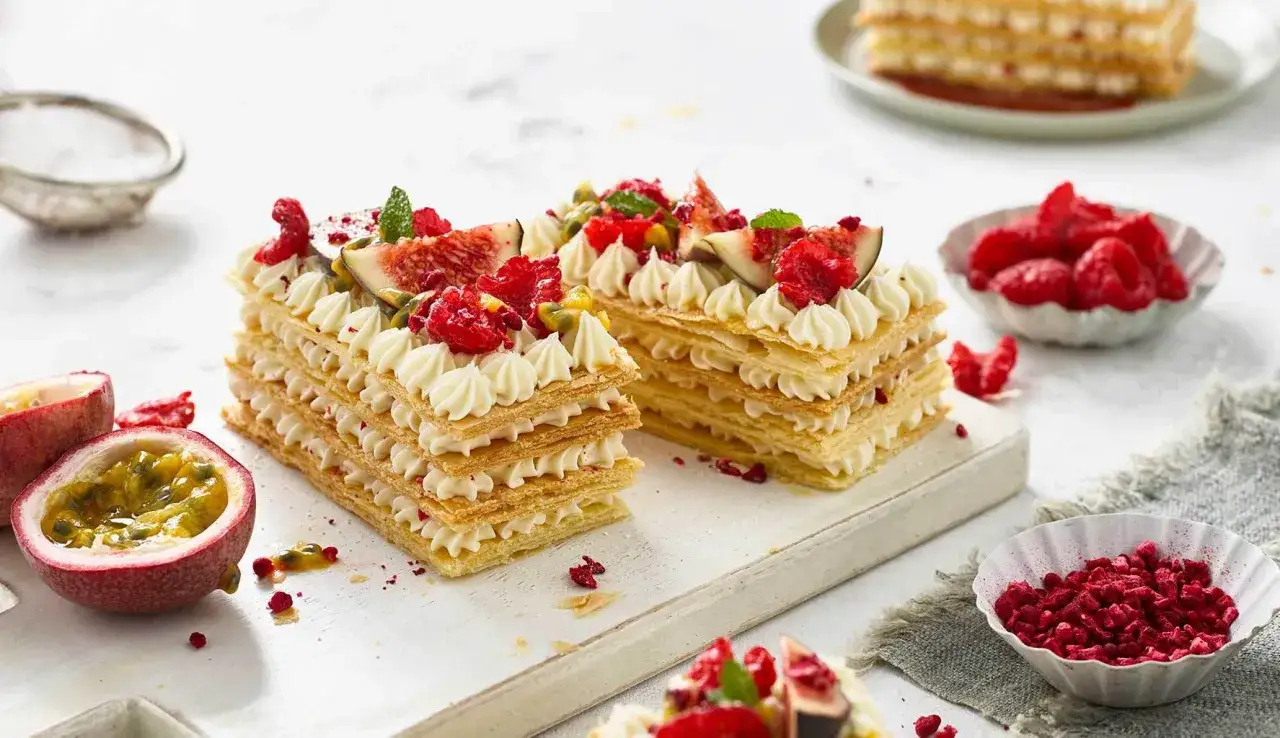 Delizioso millefoglie con frutta fresca: lamponi, fichi e frutto della passione, guarnito con panna montata.