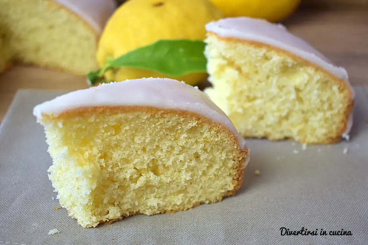 Fette di babka cytrynowa con glassa al limone, su sfondo di limoni freschi.