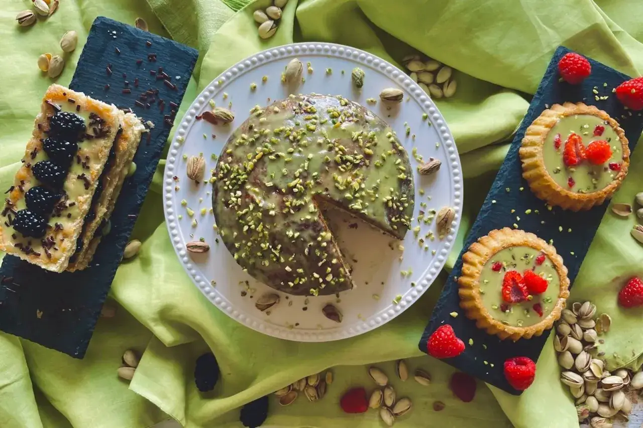Torta e tartellette con goloso krem pistacjowy, decorati con pistacchi e frutti di bosco.