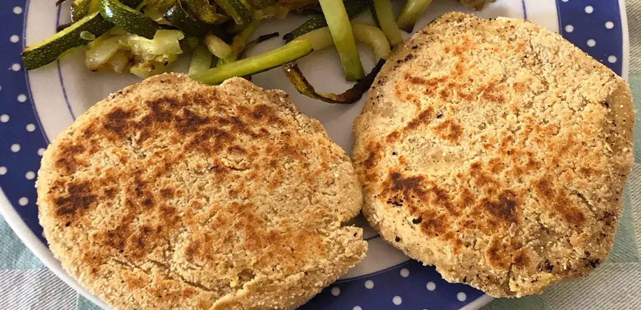 Due medaglioni di ceci dorati e croccanti, serviti con zucchine saltate. Un piatto gustoso e salutare.