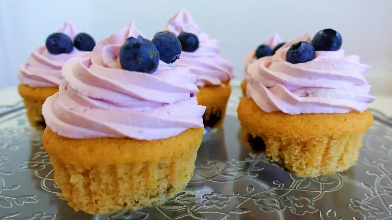 Deliziosi cupcake con glassa rosa e mirtilli freschi, perfetti per ogni occasione.