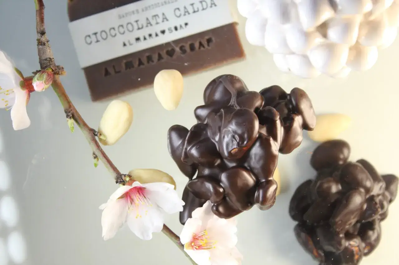 Mandorle al cioccolato, la ricetta della nonna. Fiori di mandorlo e sapone al cioccolato completano la scena.