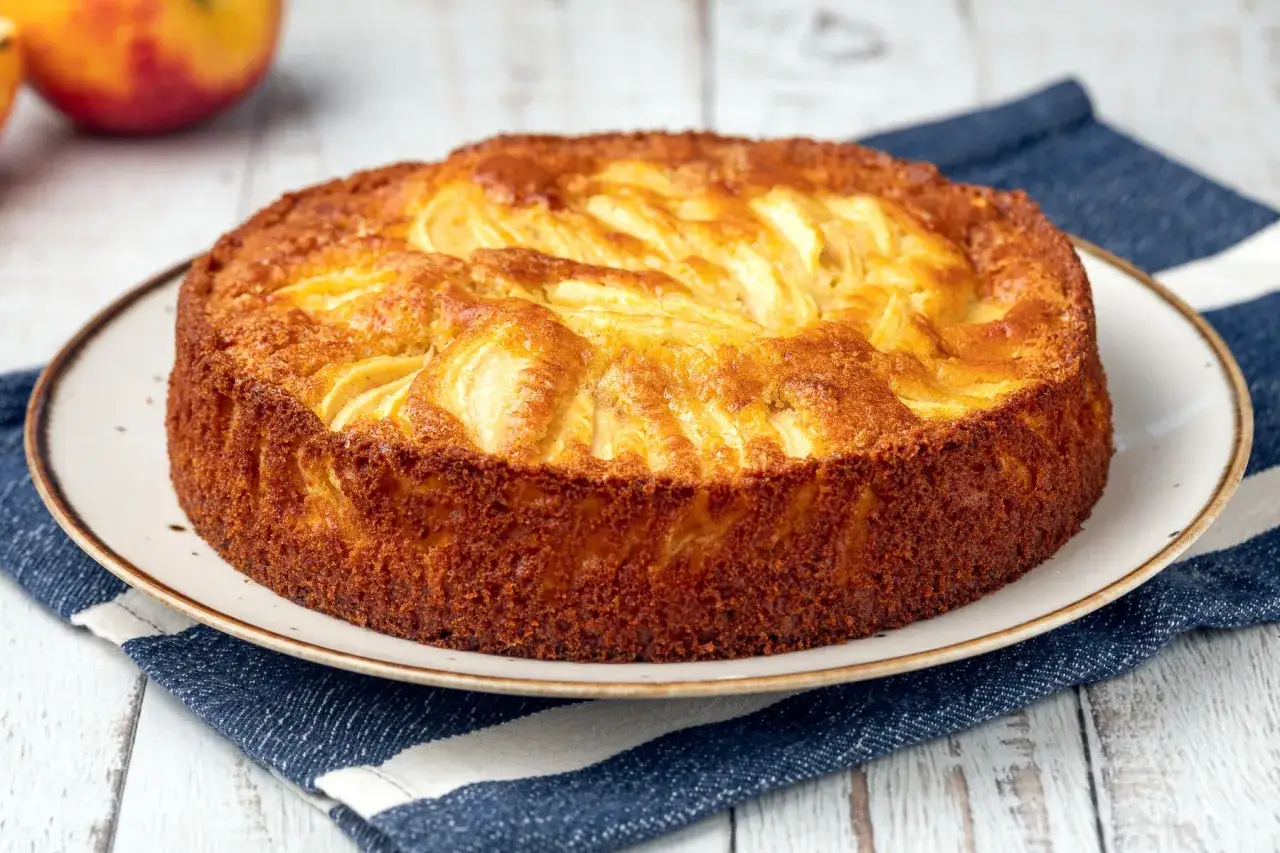 Torta di mele dorata, un dolce veloce e delizioso, con mele affettate disposte a raggiera sulla superficie croccante.