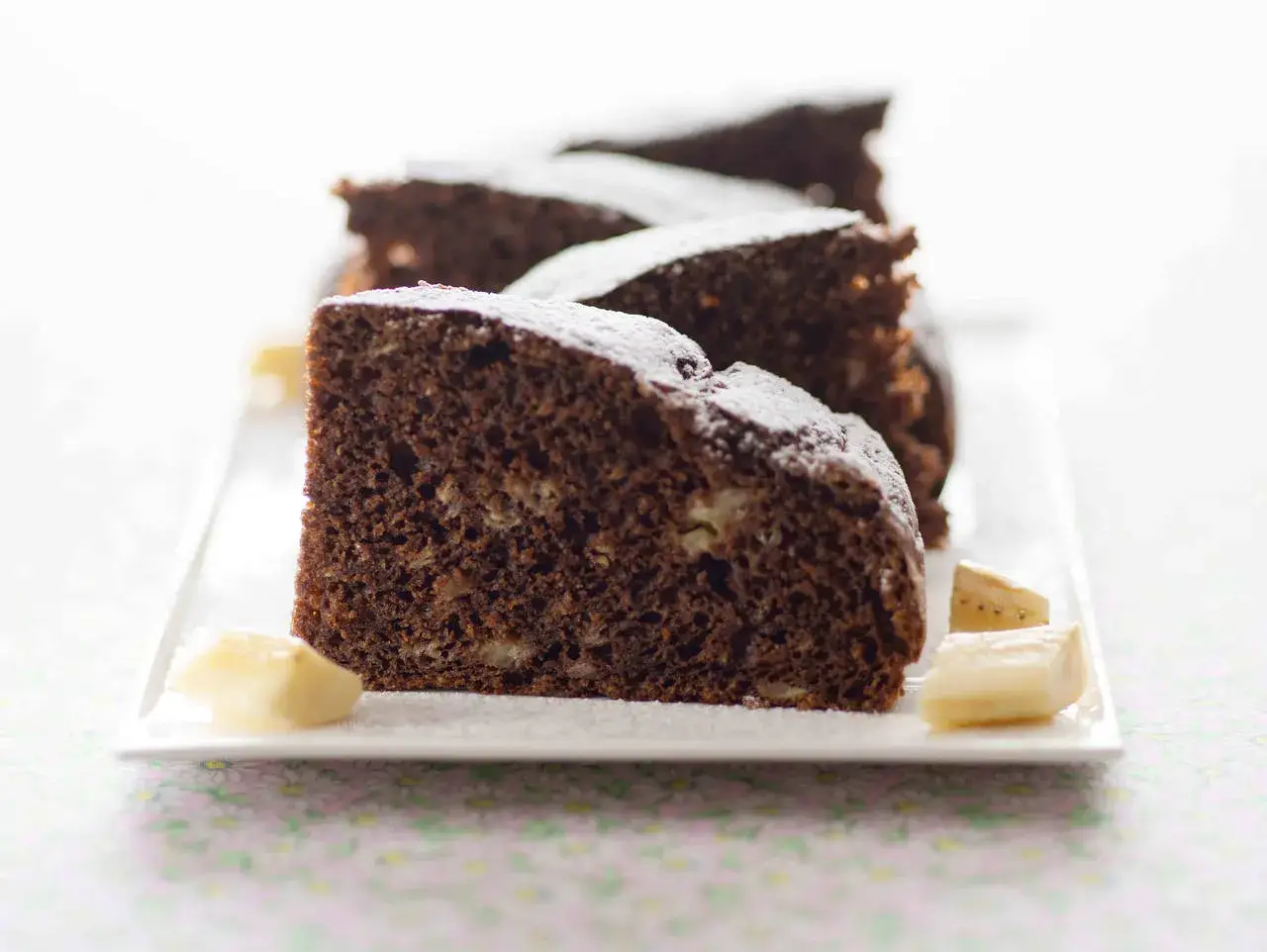 Fette di torta al cioccolato, come un kopiec kreta (montagna di talpa), cosparse di zucchero a velo e accompagnate da cubetti di banana.