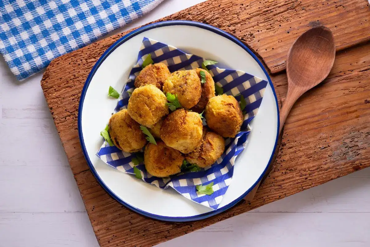 Deliziose polpette di carciofi alla siciliana, dorate e croccanti, servite su un piatto con tovagliolo a scacchi blu.