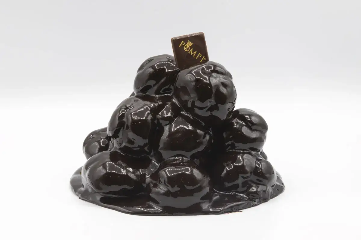 Una piramide di bign&egrave; ricoperti di cioccolato lucido, perfetta per un compleanno. La torta profitterol &egrave; decorata con un quadratino di cioccolato con il logo 