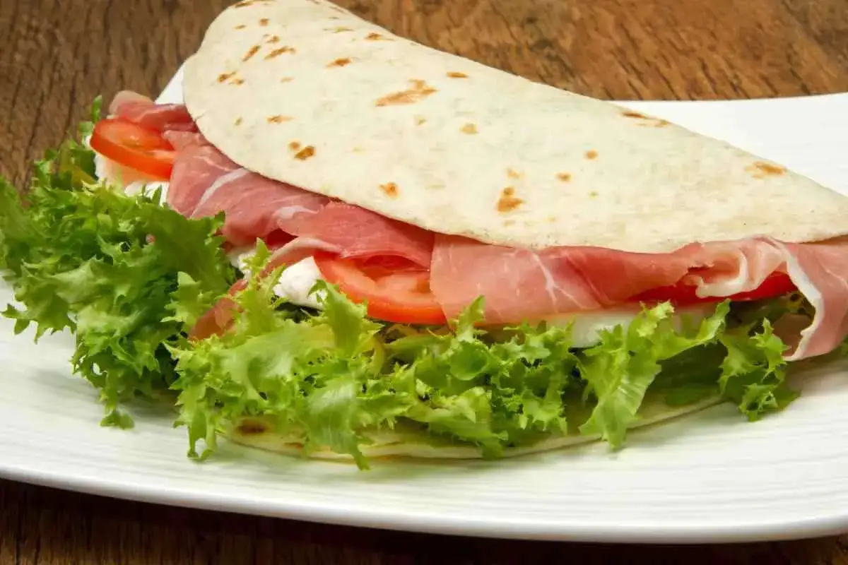 Spianata sarda farcita con prosciutto, pomodoro, lattuga e formaggio fresco. Un'idea gustosa su spianata sarda come farcirla.