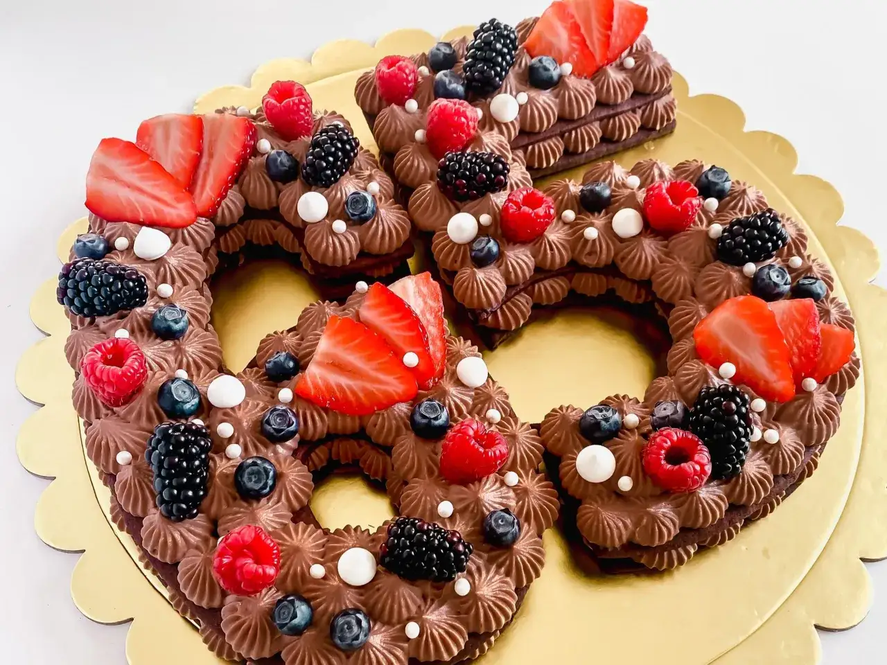 Deliziosa cream tart a forma di numeri, con pasta biscotto al cacao, crema al cioccolato e frutti di bosco freschi.