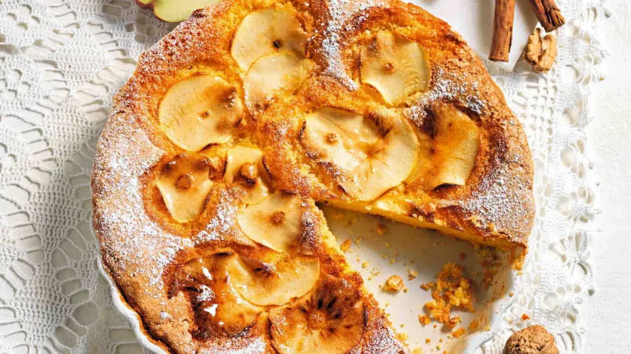 Una deliziosa torta paradiso alle mele, cosparsa di zucchero a velo, con fette di mela caramellate in superficie.