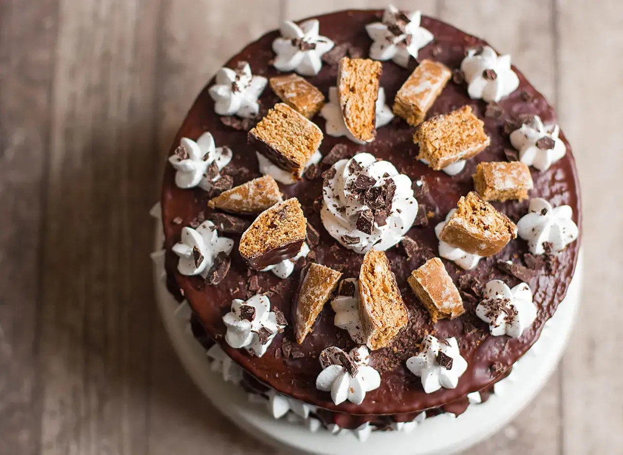 Deliziosa cream tart senza lattosio con glassa al cioccolato, panna montata e biscotti croccanti.