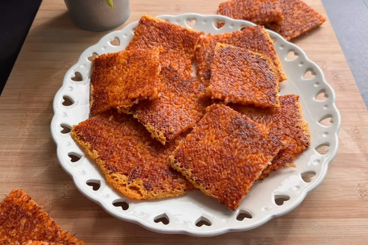 Schiacciata di riso croccante, dorata e invitante, servita su un piatto bianco decorato con cuoricini. Perfetta per uno snack goloso.