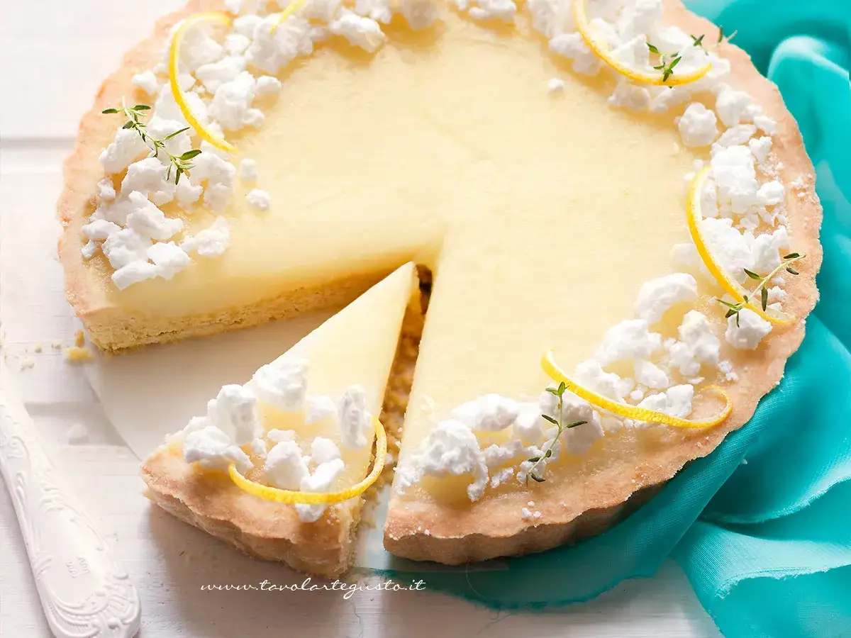 Torta con ganache al limone, decorata con meringhe e scorzette di limone.