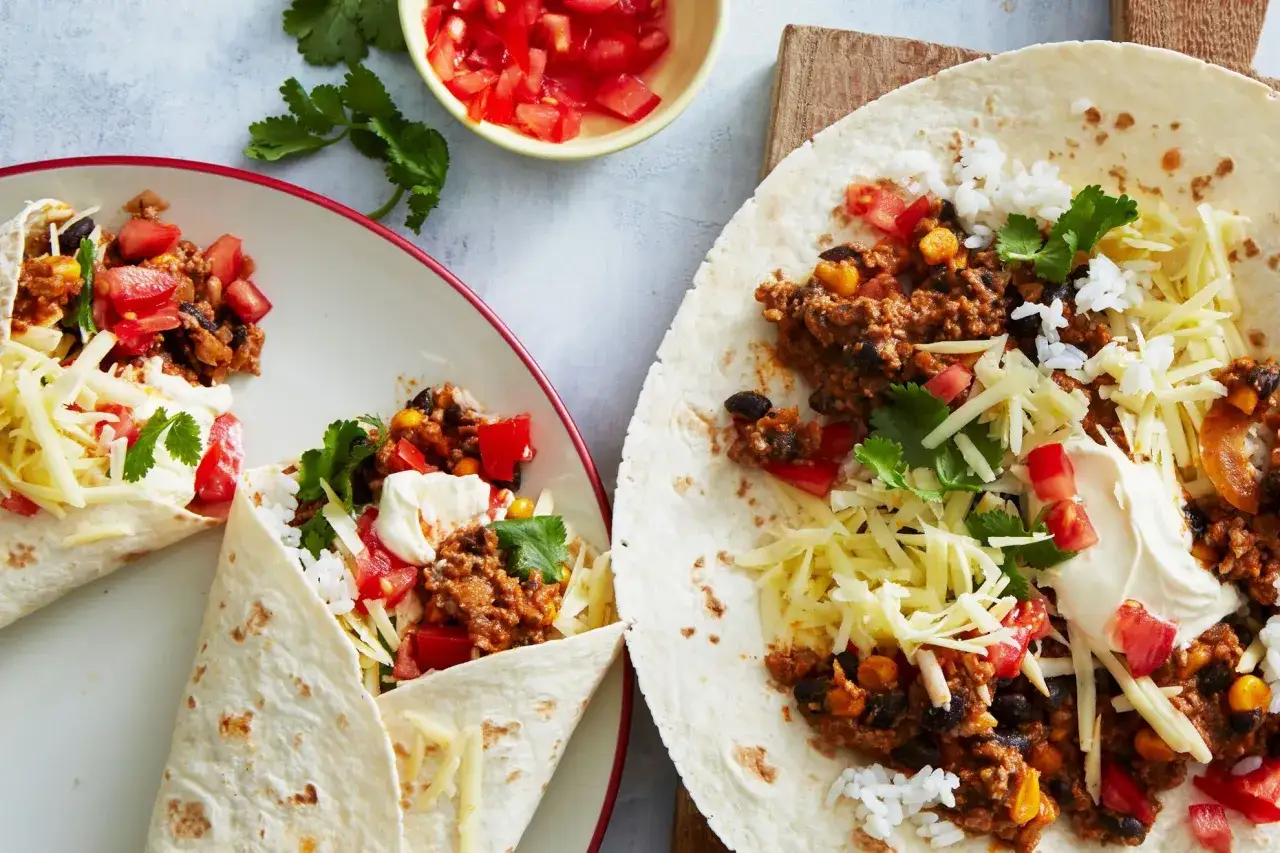 Due burrito chili con carne ripieni di carne macinata, fagioli neri, mais, riso, formaggio grattugiato, pomodoro e coriandolo.