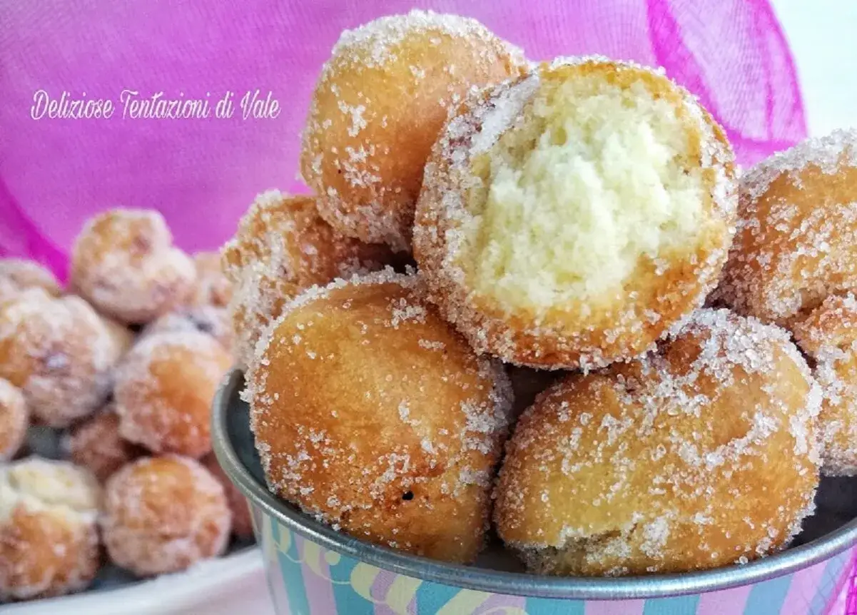 Deliziose castagnole con yogurt greco, dorate e cosparse di zucchero, pronte per essere gustate.
