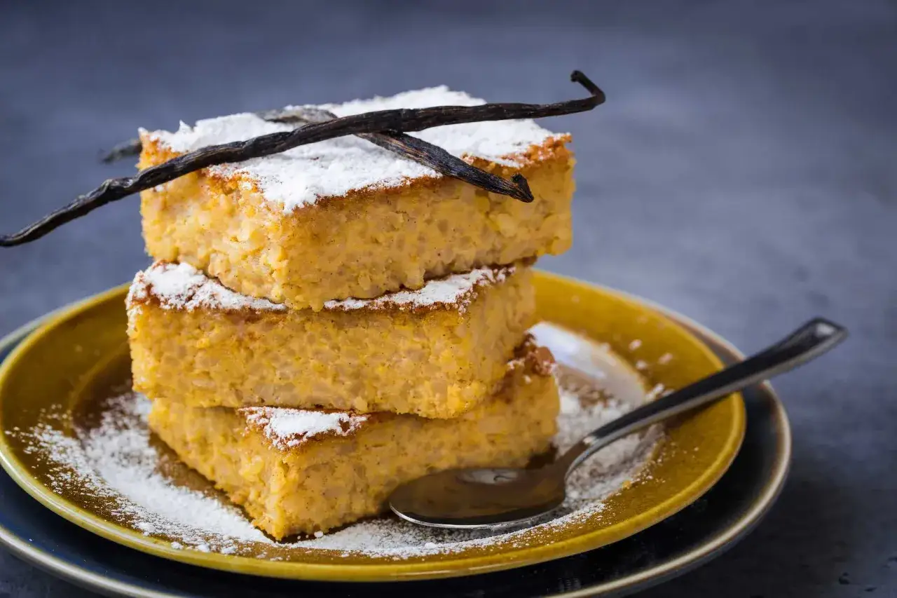 Tre fette impilate di torta di riso fiorentina, spolverate di zucchero a velo e decorate con baccelli di vaniglia.