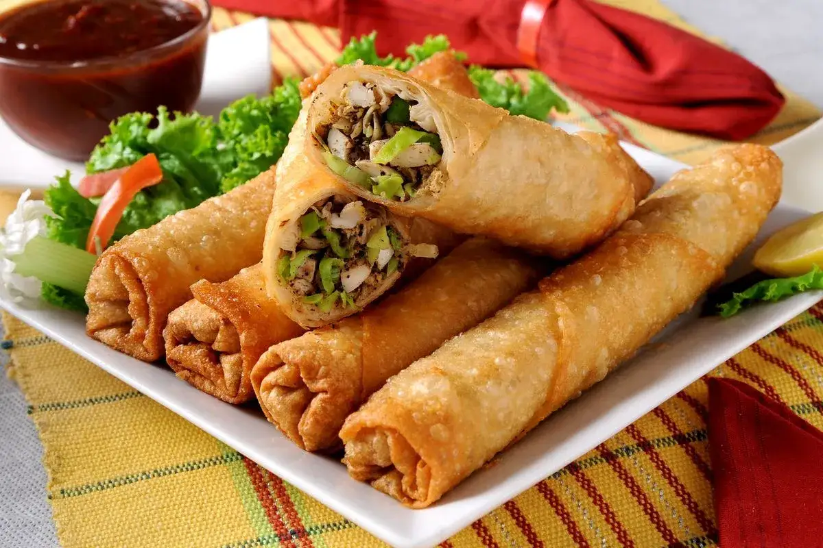 Involtini primavera croccanti con pasta fillo e carne macinata, serviti con salsa e insalata fresca.
