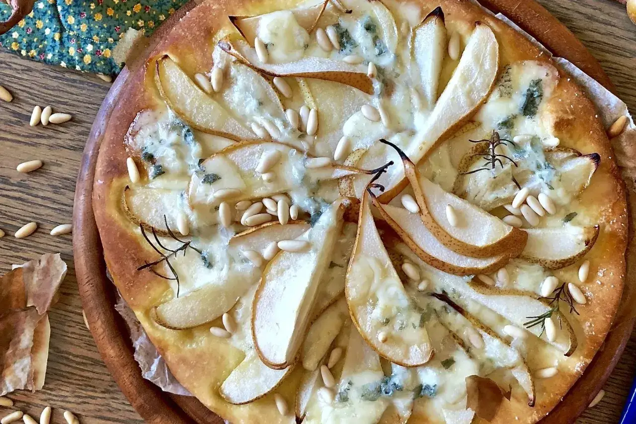 Pizza zola e pere, un connubio di sapori dolci e salati, con pinoli croccanti e un tocco di rosmarino.