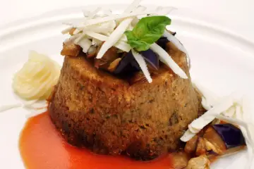 Sformato di melanzane leggero, guarnito con scaglie di formaggio, basilico e servito con salsa rossa e purè.