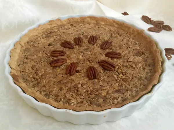 Torta di noci croccante e dorata, decorata con noci intere disposte a cerchio. Un delizioso pandi noci pronto da gustare.