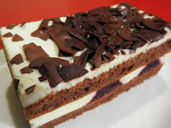 Una fetta di torta foresta nera di Montersino, con pan di Spagna al cacao, panna montata e ciliegie, decorata con riccioli di cioccolato.
