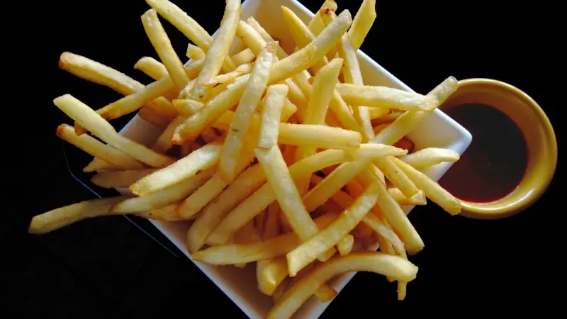 Un piatto di croccanti patatine fritte, perfette per un aperitivo, con una ciotolina di salsa rossa. Un classico intramontabile, come i veri frytki po włosku.