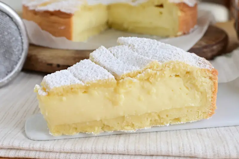 Fetta di crostata con abbondante crema allo yogurt, cosparsa di zucchero a velo.